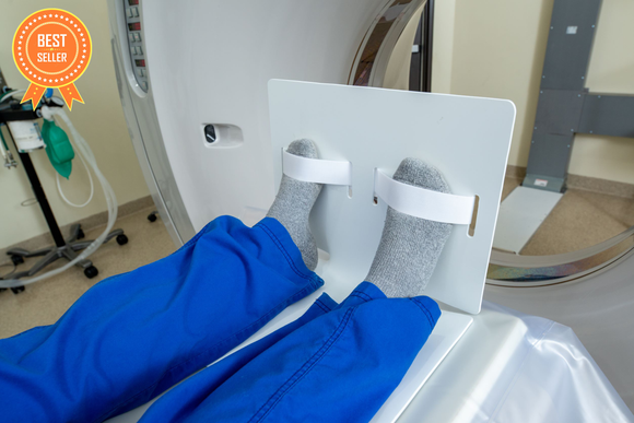 A picture of a patient's feet strapped into a Domico Med-Device SteadyPed while lying on the bed of a CT machine.